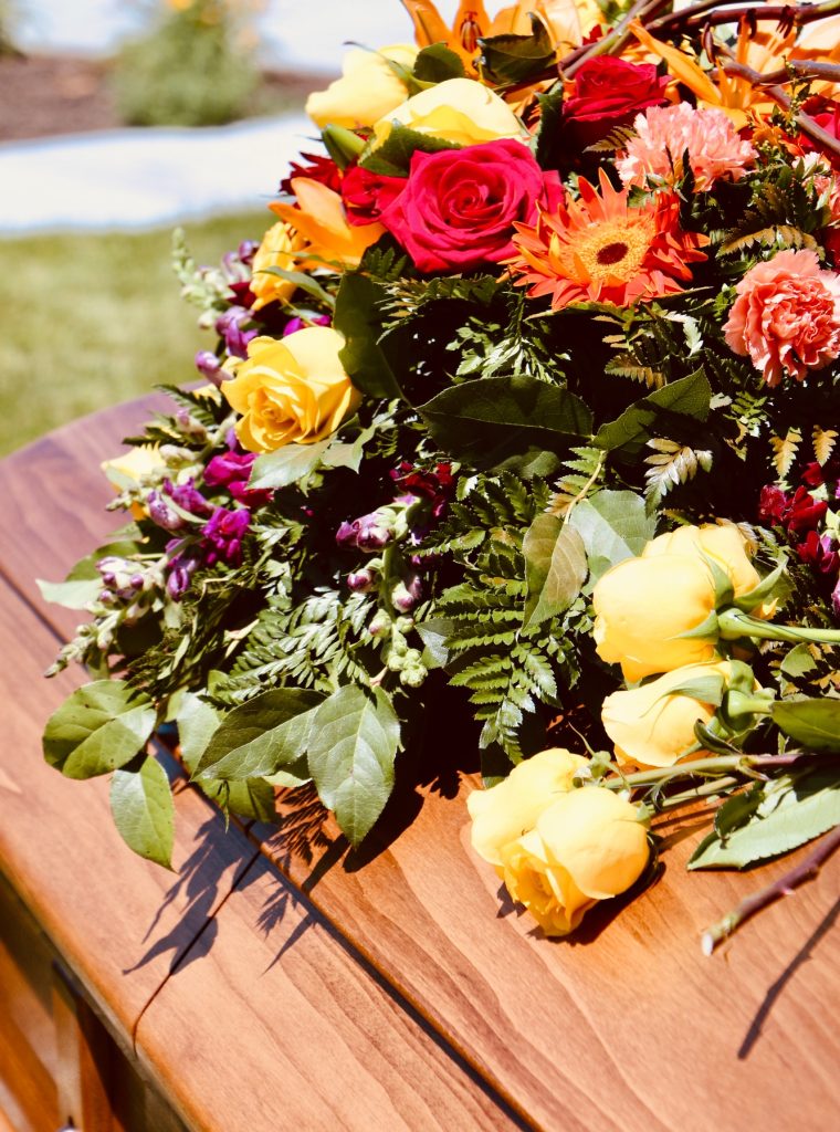 Lovely floral arrangement on wood casket.