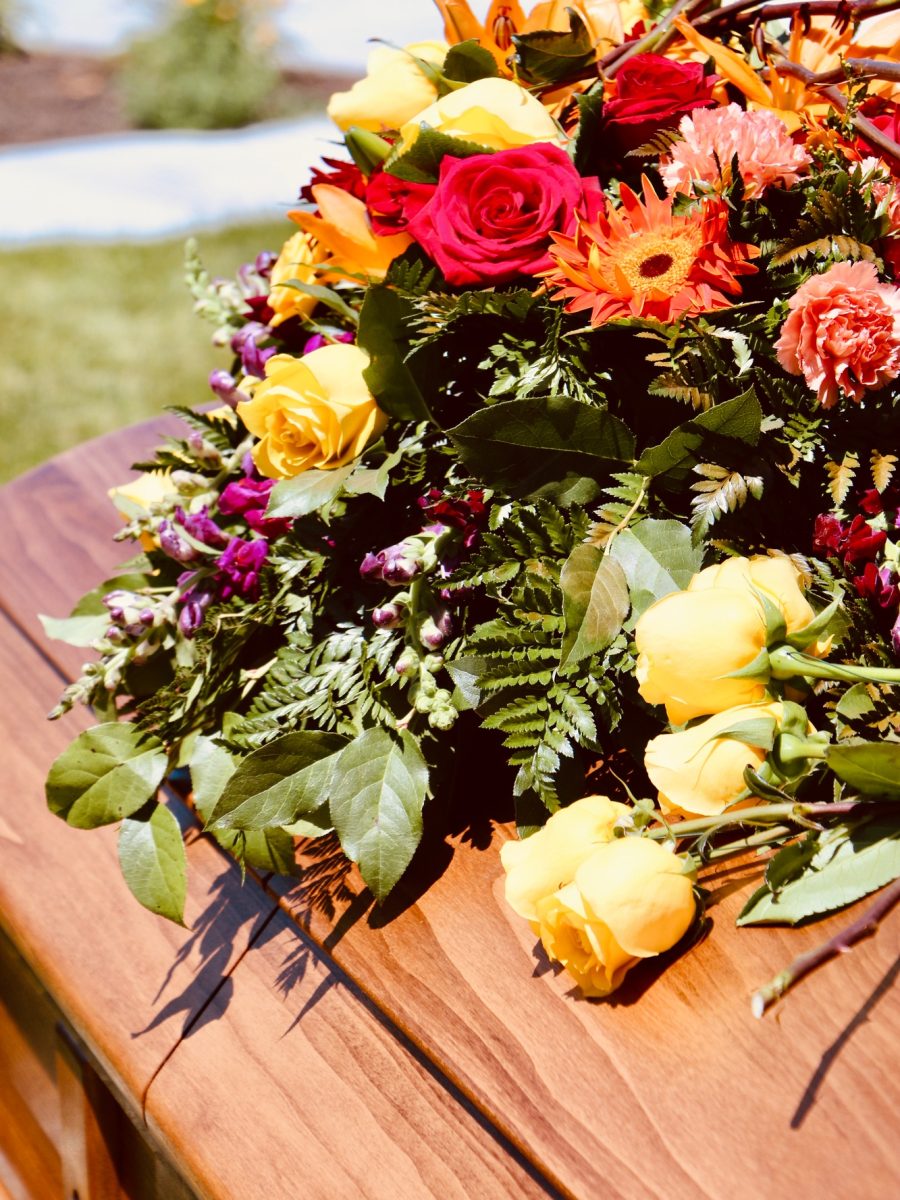 Lovely floral arrangement on wood casket.