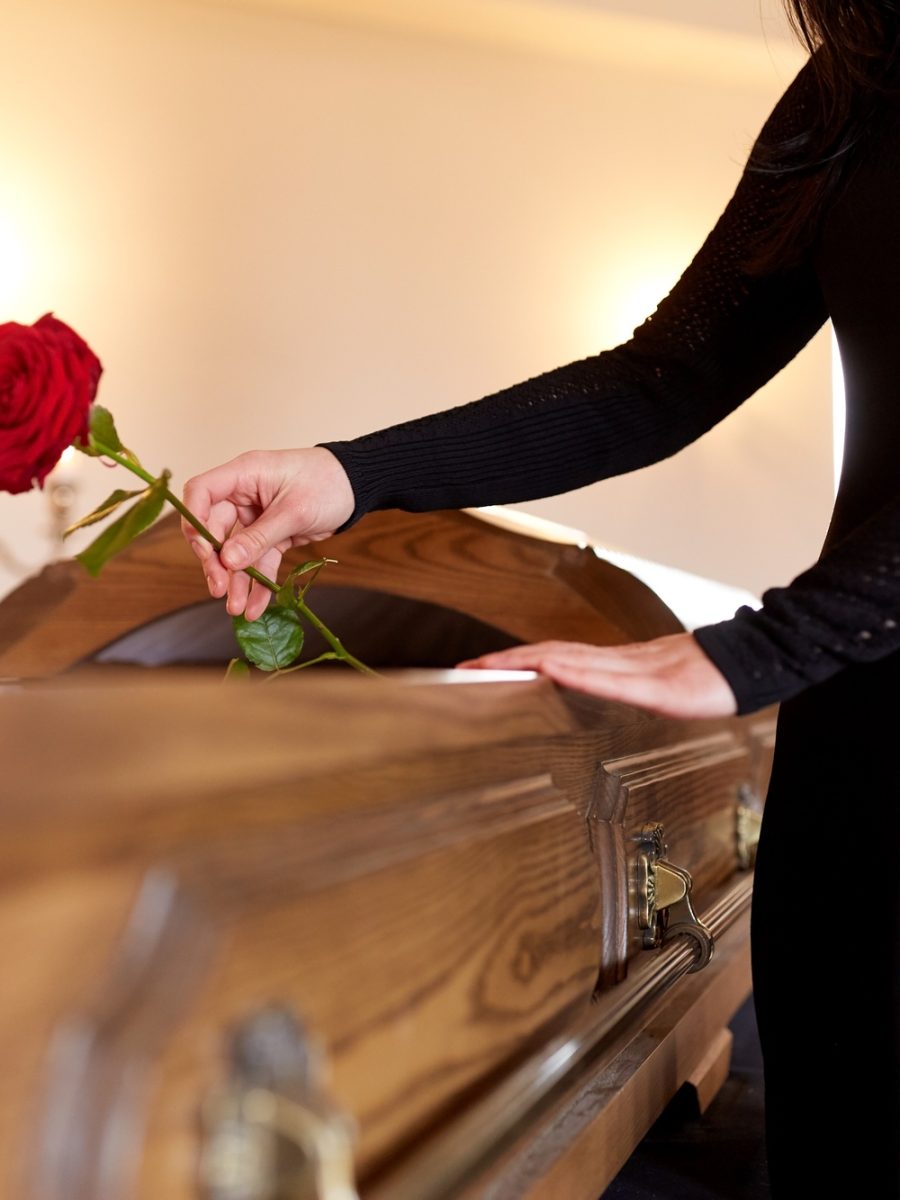 woman with red roses and coffin at funeral